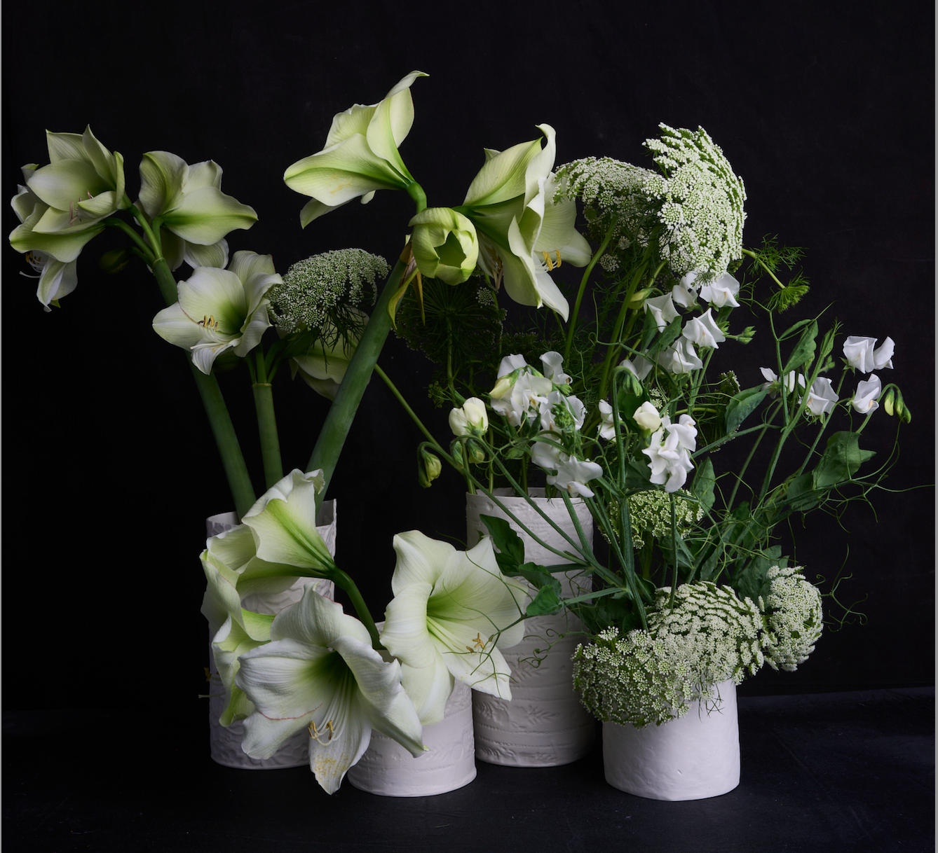 Bouquet of white and green flowers in small white vases on a black background